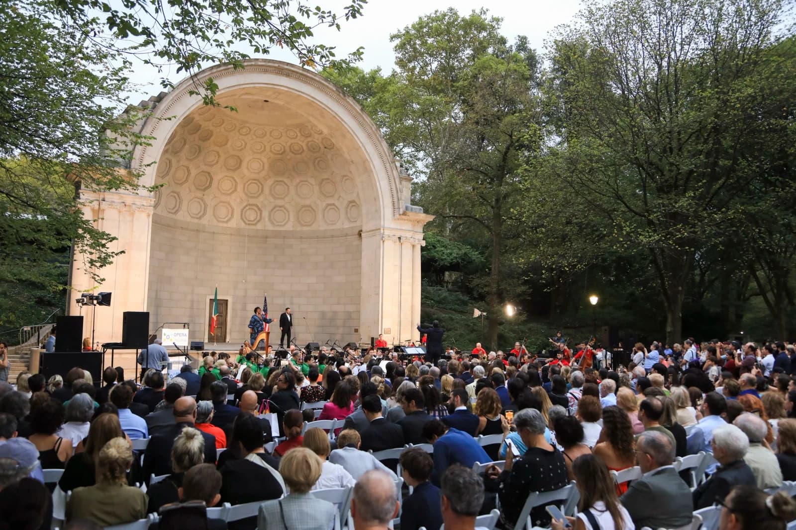 An audience gathered around an outdoor bandshell for Opera Italiana is in the Air